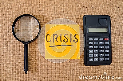 `crisis` on a sticker with a calculator and a magnifying glass. Stock Photo