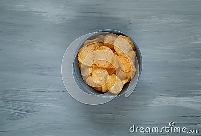 Crisps in a blue bowl on a light blue background, space for text.Convenient snack concept Stock Photo
