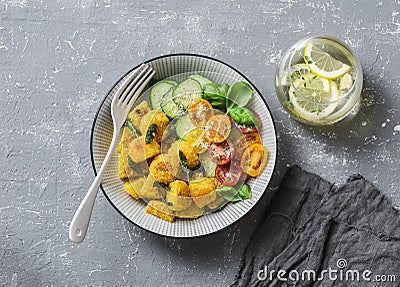 Crispy baked slices of polenta with sage butter and vegetables cucumbers, tomatoes, basil salad on a gray background, top view. Stock Photo