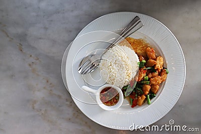 Crispy Chicken with Basil In a white circular dish Placed on a marble table Stock Photo