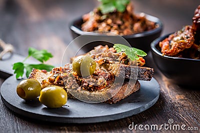 Crispy crostini with tapenade and ingredients. Tapenade - delicious olive paste, French cuisine Stock Photo
