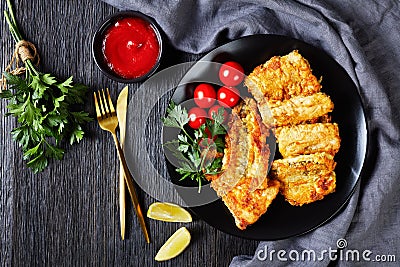 Crispy fried hake fish fillet on a black plate Stock Photo