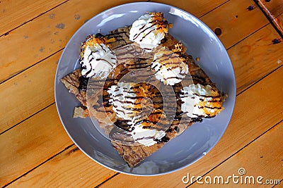 Crispy Roti with whipped cream, chocolate sauce and golden threads on top. Stock Photo