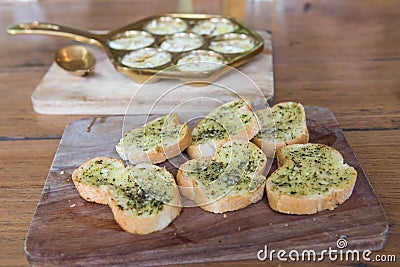 Crispy toasted bread with garlic butter and dill on wooden plate Stock Photo