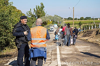 Croatian policeman and NGO Volunteer looking at migrants crossing the Serbia Croatia border in Berkasovo Bapska Editorial Stock Photo