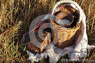 A crock of milk in a handmade wicker basket and a half loaf of rye bread Stock Photo