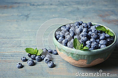 Crockery with juicy fresh blueberries and green leaves Stock Photo