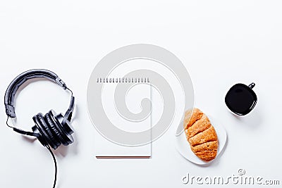 Croissant, coffee, headphones and notebook on white table Stock Photo