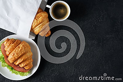 Croissant with ham and lettuce, coffee on a dark background. Stock Photo