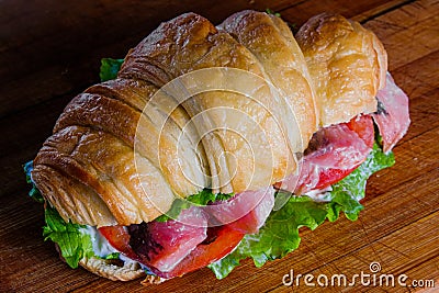 Croissant sandwiche with salmon red fish on a wooden background Stock Photo