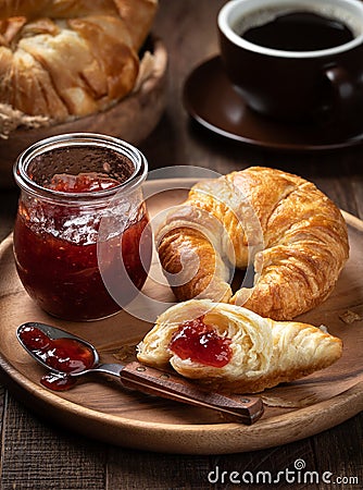 Croissant with strawberry preserves on wooden plate Stock Photo