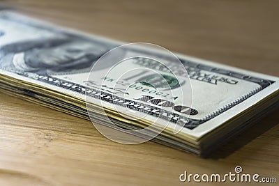 Crolled stack of 100 new dollar bills on wooden background Stock Photo