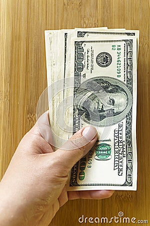 Crolled stack of 100 new dollar bills on wooden background Stock Photo