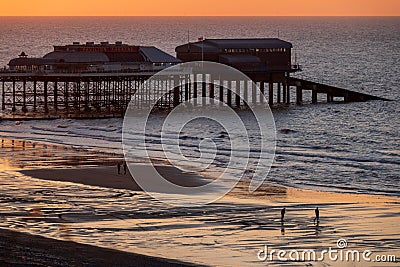 Cromer Pier at sunset with people walking on the beach Stock Photo