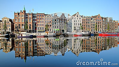 Crooked and colorful heritage buildings and houseboats, overlooking Amstel river with perfect reflections, Amsterdam Stock Photo