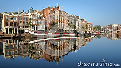 Crooked and colorful heritage buildings and houseboats, overlooking Amstel river with perfect reflections, Amsterdam Stock Photo