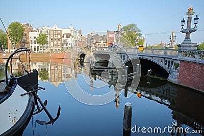 Crooked and colorful heritage buildings and houseboats, overlooking Amstel river with perfect reflections, with Blauwbrug bridge Stock Photo