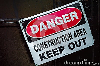 Crooked old metal warning sign that reads DANGER CONSTRUCTION AREA KEEP OUT Stock Photo