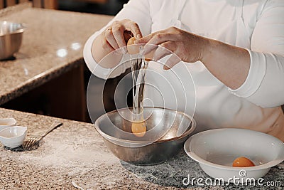 Crop female cook cracking egg into bowl Stock Photo