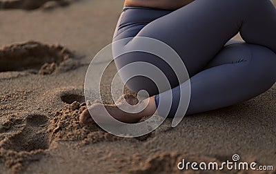 Crop anonymous woman performing Shoelace yoga pose on sandy seashore Stock Photo