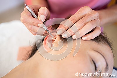 Crop chiropractor massaging ear of woman during auriculotherapy in beauty salon Stock Photo