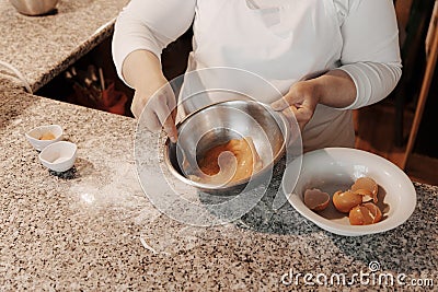 Crop female cook cracking egg into bowl Stock Photo