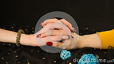 Crop girl& x27;s hand and woman& x27;s hand with different manicure. Unrecognizable females showing nail polish on black Stock Photo