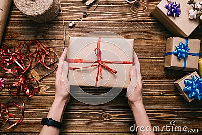 Crop hands holding wrapped present on table Stock Photo