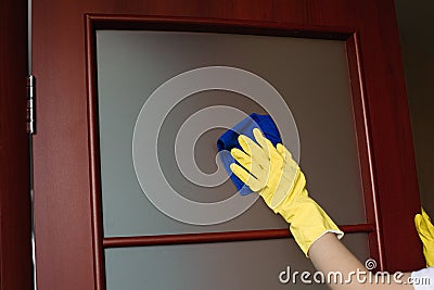 Crop of housewife hands wearing yellow gloves, cleaning dirty window. Stock Photo