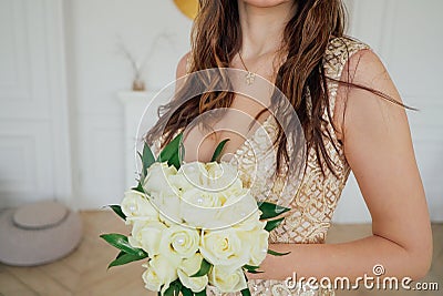 Crop photo of bride in beautiful golden dress with wedding bouquet of white roses in hands, close up Stock Photo