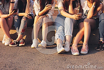 Crop photo of group of young happy tan girls real friends using mobile on sunset background Stock Photo