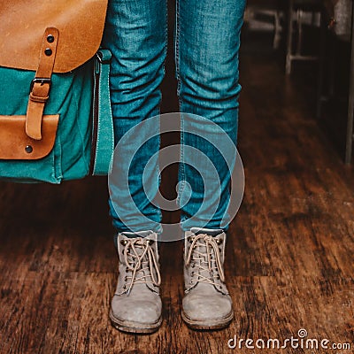 Crop photo of young woman feet girl traveler in jeans and boots with backpack indoors Stock Photo