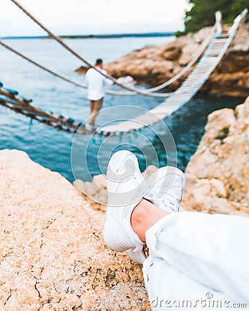 crop picture woman legs at cliff suspension bridge on background Stock Photo