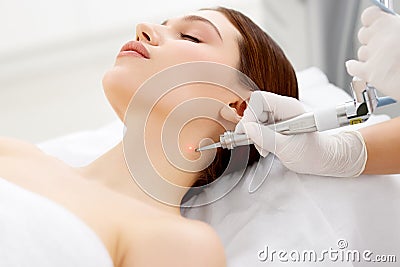 Cosmetologist removing mole with laser machine Stock Photo