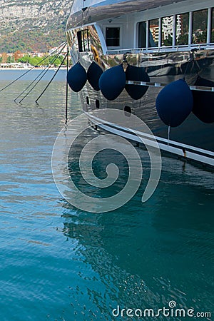Crop view of luxury motorboat with fenders on calm water parked in the marina, turquoise sea Stock Photo