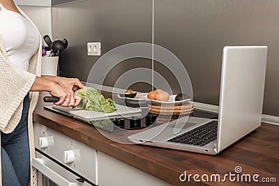 Crop woman cooking lunch and watching video on laptop Stock Photo