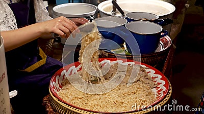 Crop woman putting noodles in bag. Unrecognizable female seller putting traditional Thai noodles in plastic bag while working in Stock Photo