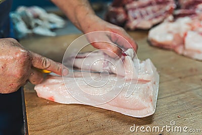 Crop worker cutting raw meat in butchery shop Stock Photo