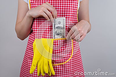 Croped close up photo of woman hiding 100 dollars into pocket of her apron isolated grey background Stock Photo