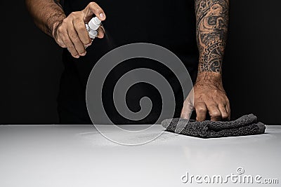 Croped image of man spraying alcohol above white table top and dark background Stock Photo