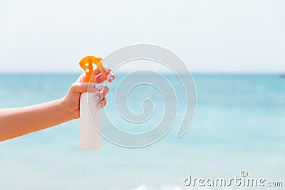 Croped image of woman`s hand holding sunblock spray at the beach Stock Photo