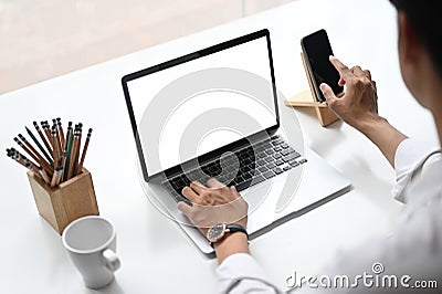 Croped shot of business woman using smartphone and laptop with white screen. Stock Photo