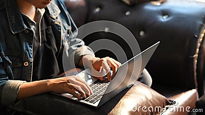 Croped shot male hands typing on laptop keyboard on while sitting on sofa. Stock Photo