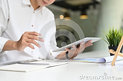 Croped shot young businessman using digital tablet for planing his strategy on white table. Stock Photo