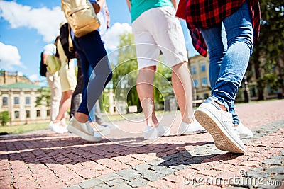 Cropped close up low angle photo shot of six student`s legs, walking on the cobbles. Sunny spring day, students are going to camp Stock Photo