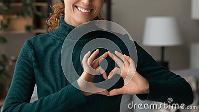 Cropped close up smiling grateful woman showing heart sign Stock Photo