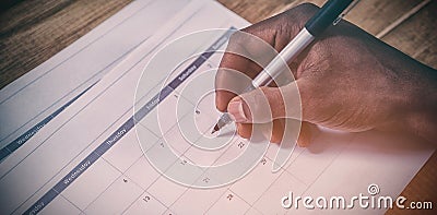 Cropped hand of businessman marking dates on calendar Stock Photo