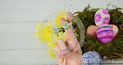 Cropped hand with creative bunny cartoon drawing on crossed fingers over easter eggs in nest Stock Photo