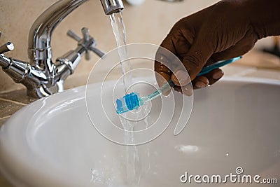 Cropped hand on man washing toothbrush in bathroom sink Stock Photo