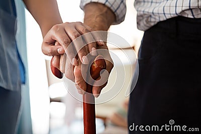 Cropped hands of female doctor and senior man holding walking cane Stock Photo